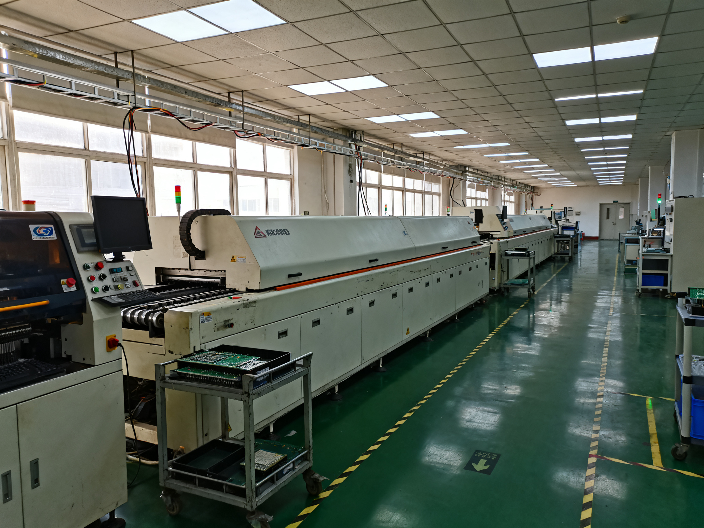 Wide documentary photo of an ordinary smt production line in a working electronics factory.