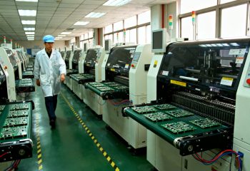 1786409269-an-engineer-walking-past-a-row-of-smt-conveyor-systems-in-a-chinese-electronics-1786409266615